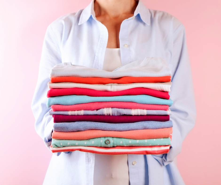 Full-Service Dry Cleaner Woman holding a stack of folded shirts.