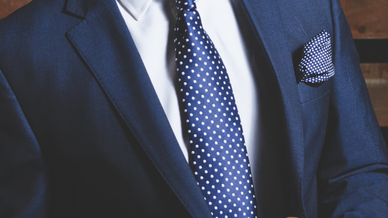 What makes a garment wrinkle-free? Man in a navy suit with a crisp white dress shirt, navy tie, and pocket square